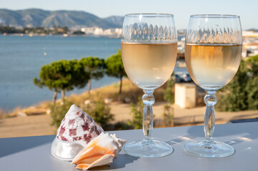 Summer on French Riviera, drinking of cold white or gris rose wine from Cotes de Provence on outdoor terrase with view on harbour of Toulon, Var, France and sea shells