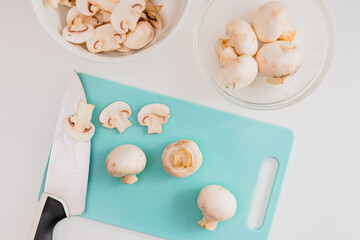 Wall Mural - Fresh raw  chopped organic white mushrooms close up on cutting board on white background, directly from above