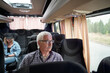© pressmaster - Serious aged man in eyeglasses sitting by window inside bus while traveling to another city