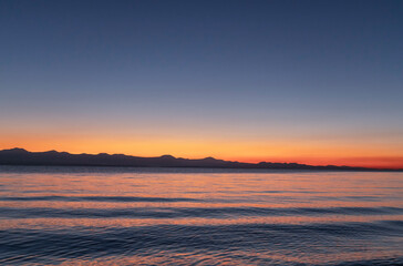 Wall Mural - beautiful bright sunset sky on the lake and silhouette mountains on the horizon.