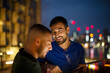 © Martin Barraud/Caia Image - Happy men with smart phone in city at night