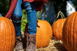 © Holly Clark/Stocksy - Girl's feet wearing boots by orange pumpkins in October