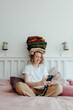 © Sergey Narevskih/Stocksy - Woman with stack of clothes using smartphone