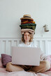 © Sergey Narevskih/Stocksy - Woman with stack of clothes using laptop
