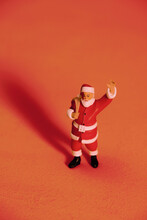 A Doll Of Santa Claus With Christmas Decoration Over Red Background