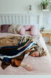 © Sergey Narevskih/Stocksy - Woman with pile of clothes on bed