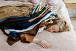 © Sergey Narevskih/Stocksy - Lying woman pinned down by pile of clothes