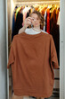© Sergey Narevskih/Stocksy - Woman holding t-shirt in dressing room