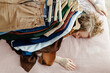 © Sergey Narevskih/Stocksy - lying woman with pile of clothes on her back