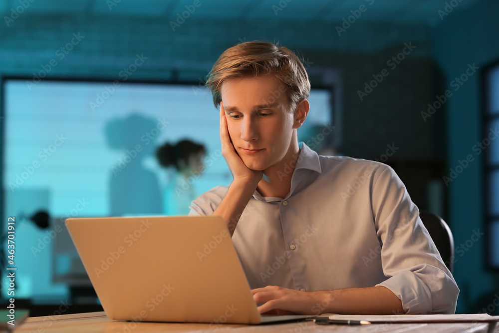 Young businessman working with laptop in office at night