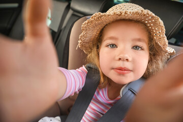 Canvas Print - Cute little girl in hat buckled in car safety seat