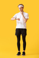 Wall Mural - Sporty male runner checking pulse on color background