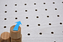 On The Edge Of A White Perforated Board, There Is A Sticky Note In The Shape Of An Arrow. Copy Space Available.