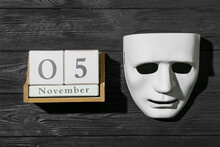 Guy Fawkes Mask And Calendar With Date Of November 5 On Dark Wooden Background