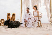 Happy Newlyweds With Dog On Beach