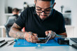 © Manu Padilla/Stocksy - Engineer using tool to fix smartphone