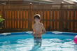 © Maria Manco/Stocksy - Portrait of happy boy in backyard pool