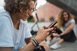 © Kike Arnaiz/Stocksy - Guy using smartphone in park