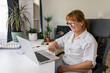 © STUDIO TAURUS/Stocksy - Happy senior woman using laptop at home