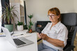 © STUDIO TAURUS/Stocksy - Senior woman using smartphone at home office