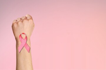 Wall Mural - First of person top view, raised female hand with a ribbon, cancer awareness