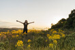 © Alba Vitta/Stocksy - Young woman standing in field with open arms
