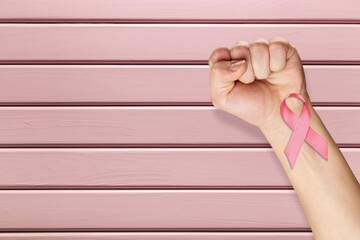 Wall Mural - First of person top view, raised female hand with a ribbon, cancer awareness