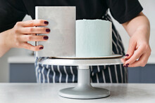 A female pastry chef makes a cake.
