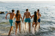 © STUDIO TAURUS/Stocksy - Group of friends running into the water