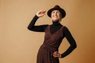 Wall Mural - Grey senior woman wearing hat and dress laughing at camera