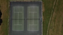 steady tripod shot of a green and black large tennis court in the middle of the countryside, this video was shot on the DJI mavic air 2 drone in england.