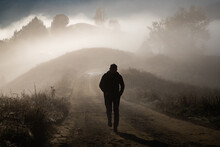 Man Walking In A Foggy Autumn Landscape