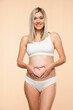 pregnent woman in lingerie making heart shape sign wut her hands in her belly