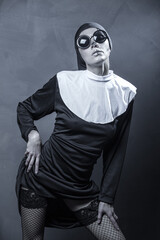 Wall Mural - Beautiful woman wearing nun costume and halloween makeup over dark gray background