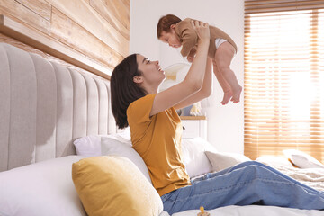 Sticker - Happy young mother with her cute baby on bed at home