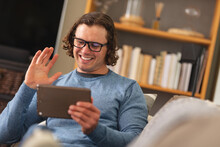 Caucasian Disabled Man Wearing Glasses Waving While Having A Video Call On Digital Tablet At Home
