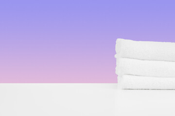 Wall Mural - Stacked clean towels on white table against color background