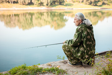 Wall Mural - senior concept. pensioner fishes on the river in his spare time. A useful hobby, outdoor activities in old age. copy space. Sits