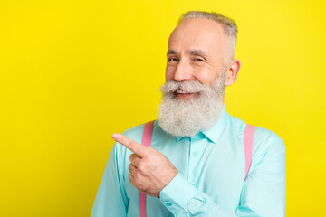 Poster - Photo of positive senior man point empty space wear blue shirt isolated on vivid yellow color background