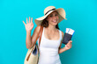 © luismolinero - Young caucasian woman holding a beach bag and passport with pamel isolated on blue background saluting with hand with happy expression