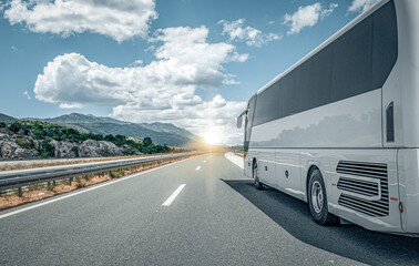 white passenger bus on the highway against the backdrop of a beautiful landscape.