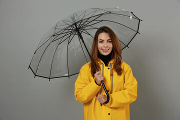 Wall Mural - Girl in yellow raincoat with transparent umbrella