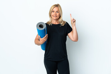 Wall Mural - Middle age woman going to yoga classes while holding a mat isolated on white background pointing up a great idea