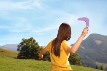 Sticker - Woman throwing boomerang in mountains, back view. Space for text