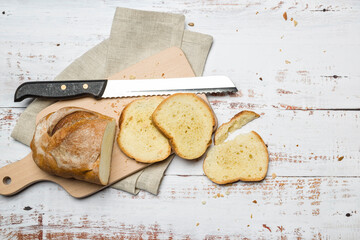 Wall Mural - Sliced fresh bread and crumbs on wooden cutting board. Top view