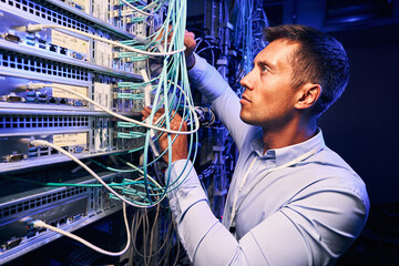 Wall Mural - Skilled focused system administrator inspecting fiberl cabling