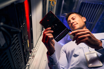 Wall Mural - Concentrated tranquil data center worker examining HDD