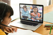 © vectorfusionart - Asian girl using laptop for video call, with smiling diverse elementary school pupils on screen