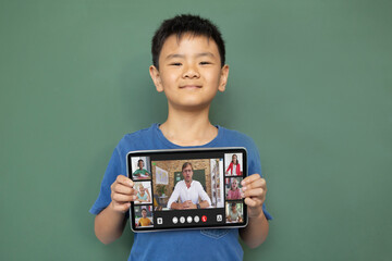 Sticker - Smiling asian boy holding tablet for video call, with smiling elementary school pupils on screen