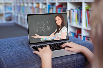 Wall Mural - Caucasian girl using laptop for video call, with smiling caucasian female teacher on screen